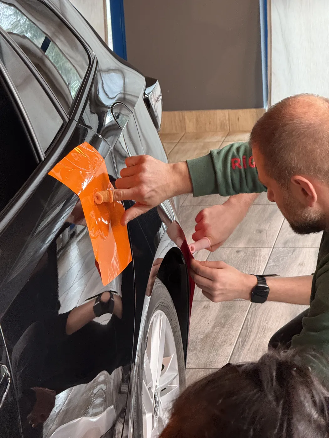 Aplikator dopasowuje pomarańczową folię przy klamce drzwi